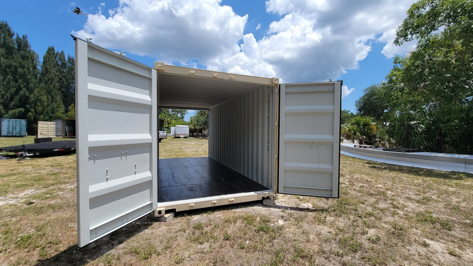 White shipping container with cargo doors open at both ends.
