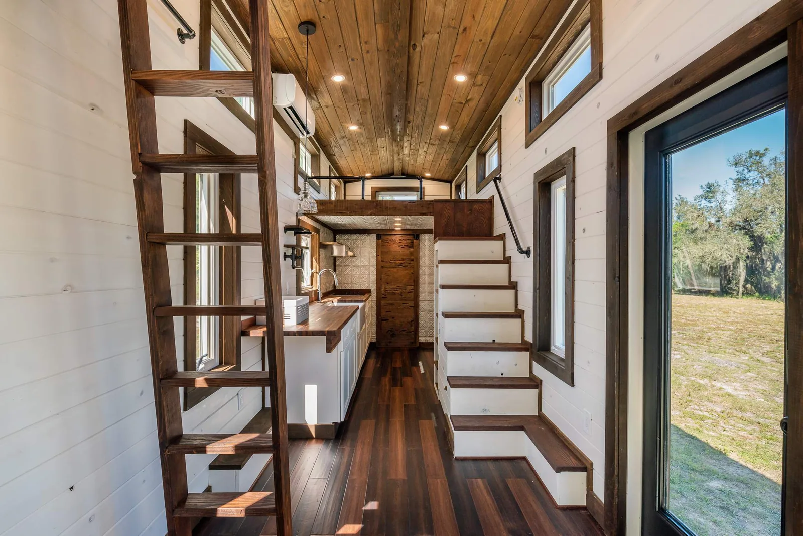 Custom wood staircase and white paneled walls in a finished tiny house.